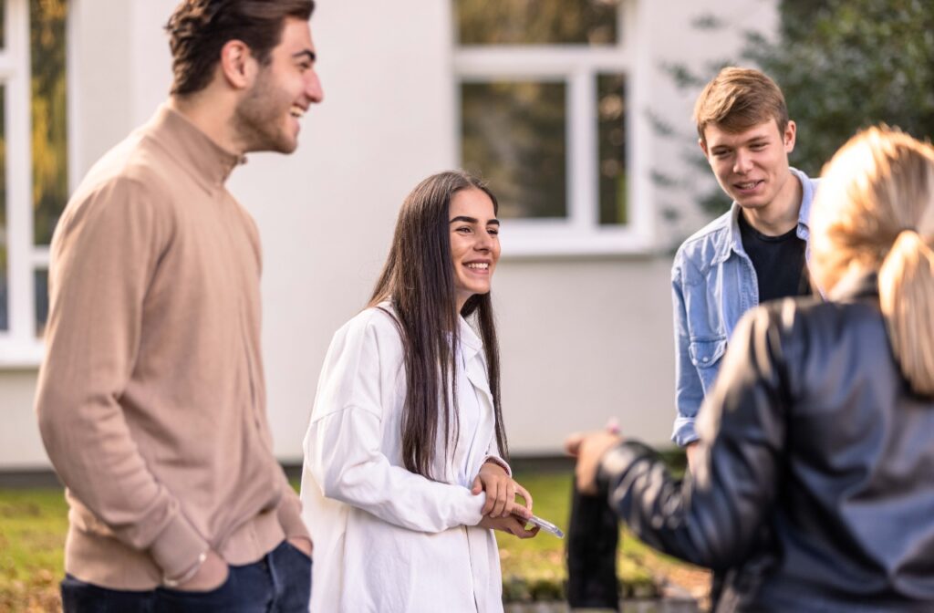 Gruppe junger Menschen unterhält sich lachend im Freien vor einem Gebäude