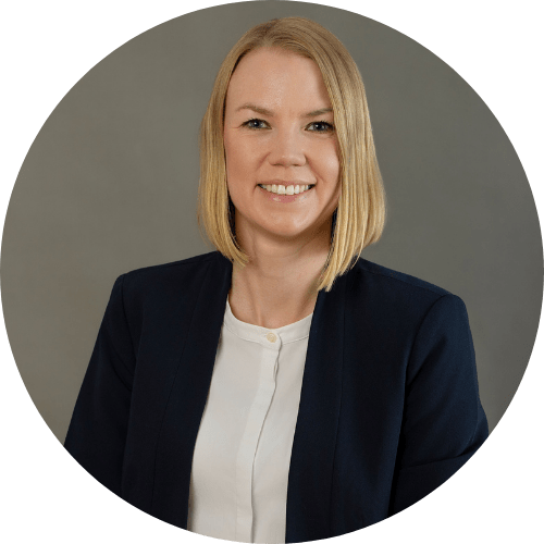 Professionelles Porträtfoto einer lächelnden Frau mit blondem Haar in dunklem Blazer