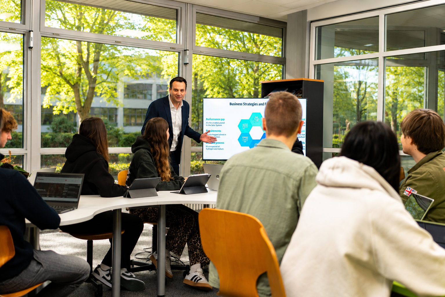 Dozent hält eine Präsentation zu Business-Strategien vor einer Gruppe von Studierenden in einem modernen Seminarraum